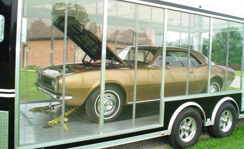 The Camaro is transported in a clear-sided trailer