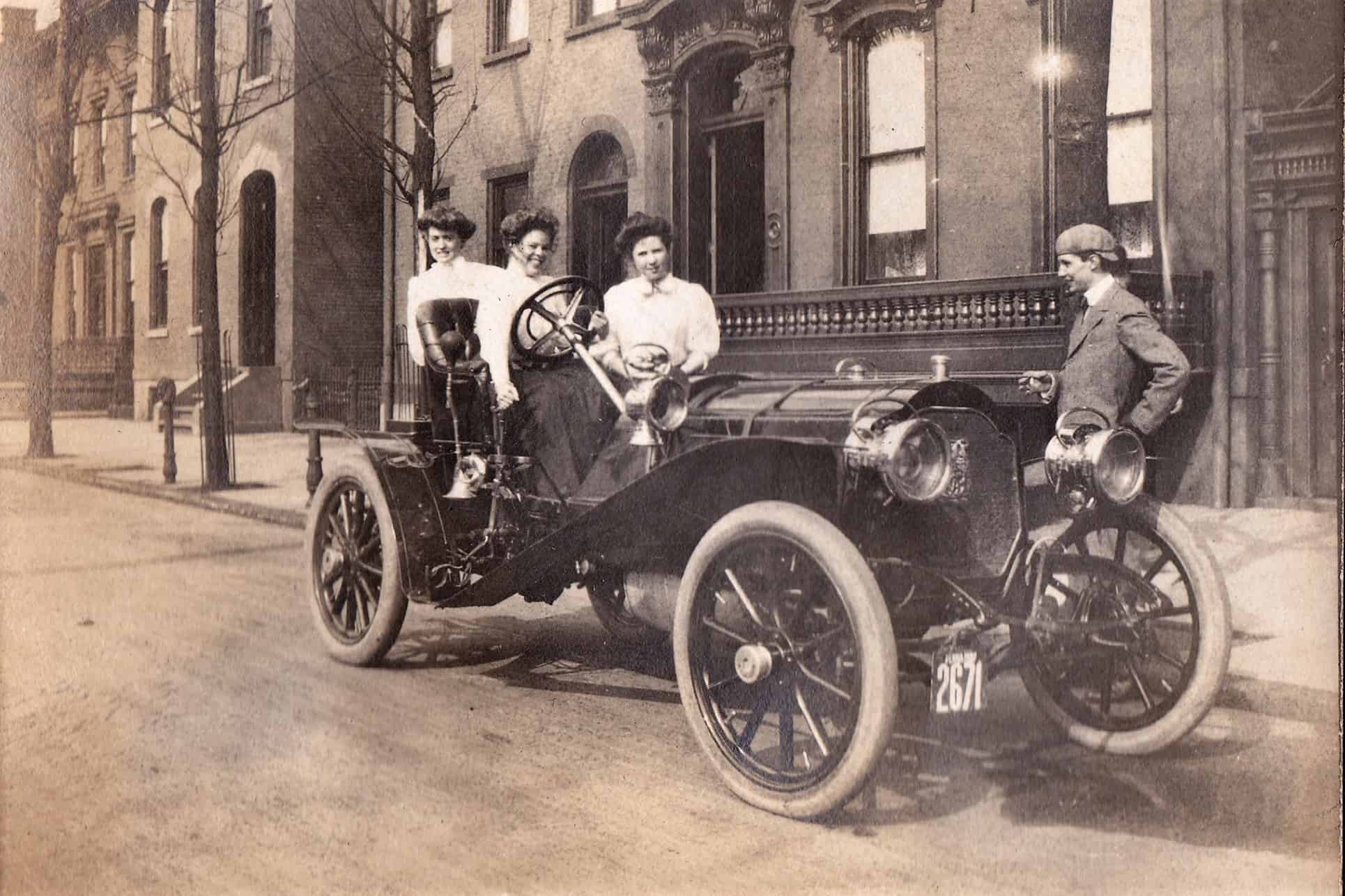 Three young ladies pose with a sporty lad's new Packard